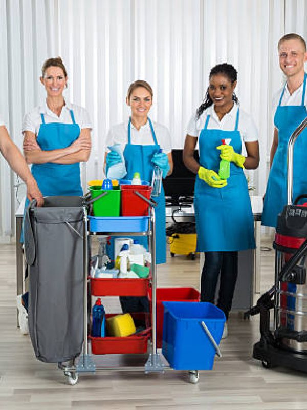 Group Of Happy Cleaners Standing With Cleaning Equipments In Office